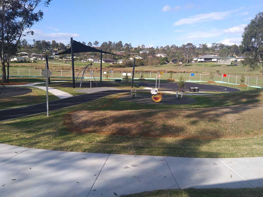 A park with a concrete walkway and a swing set