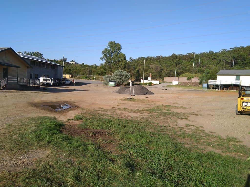 A large dirt field with a yellow truck parked in the middle of it.