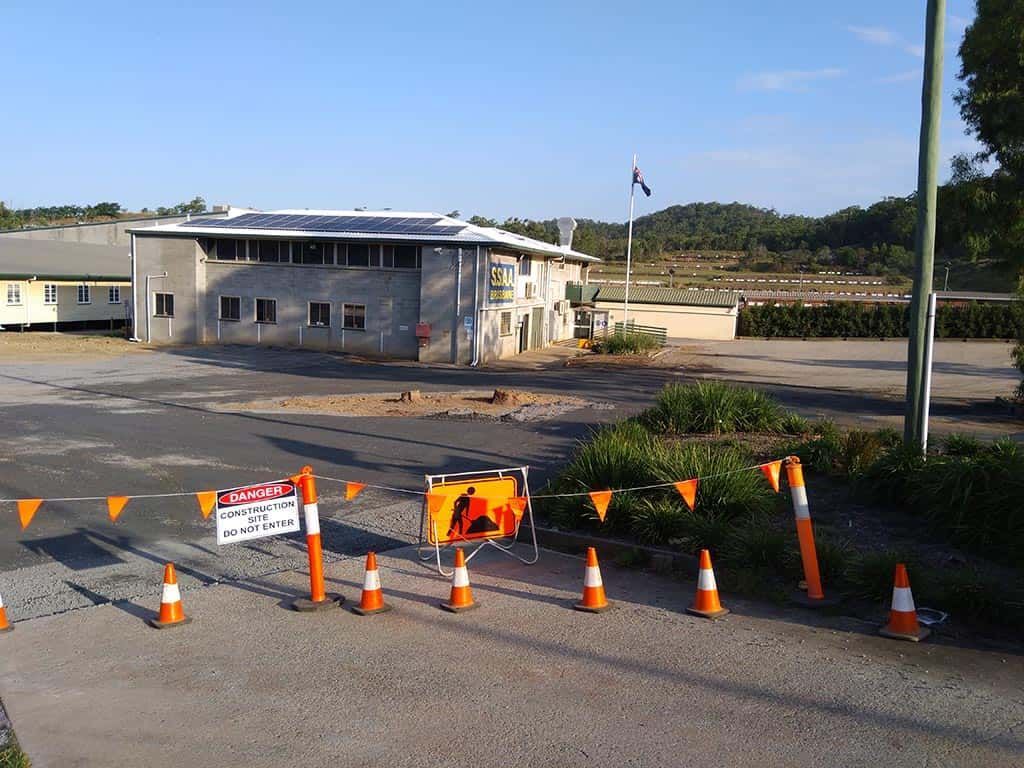 A row of orange and white traffic cones are lined up in front of a building.