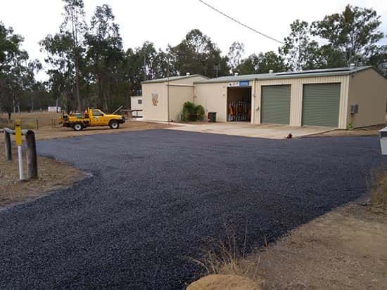 A machine is laying asphalt on the side of a road