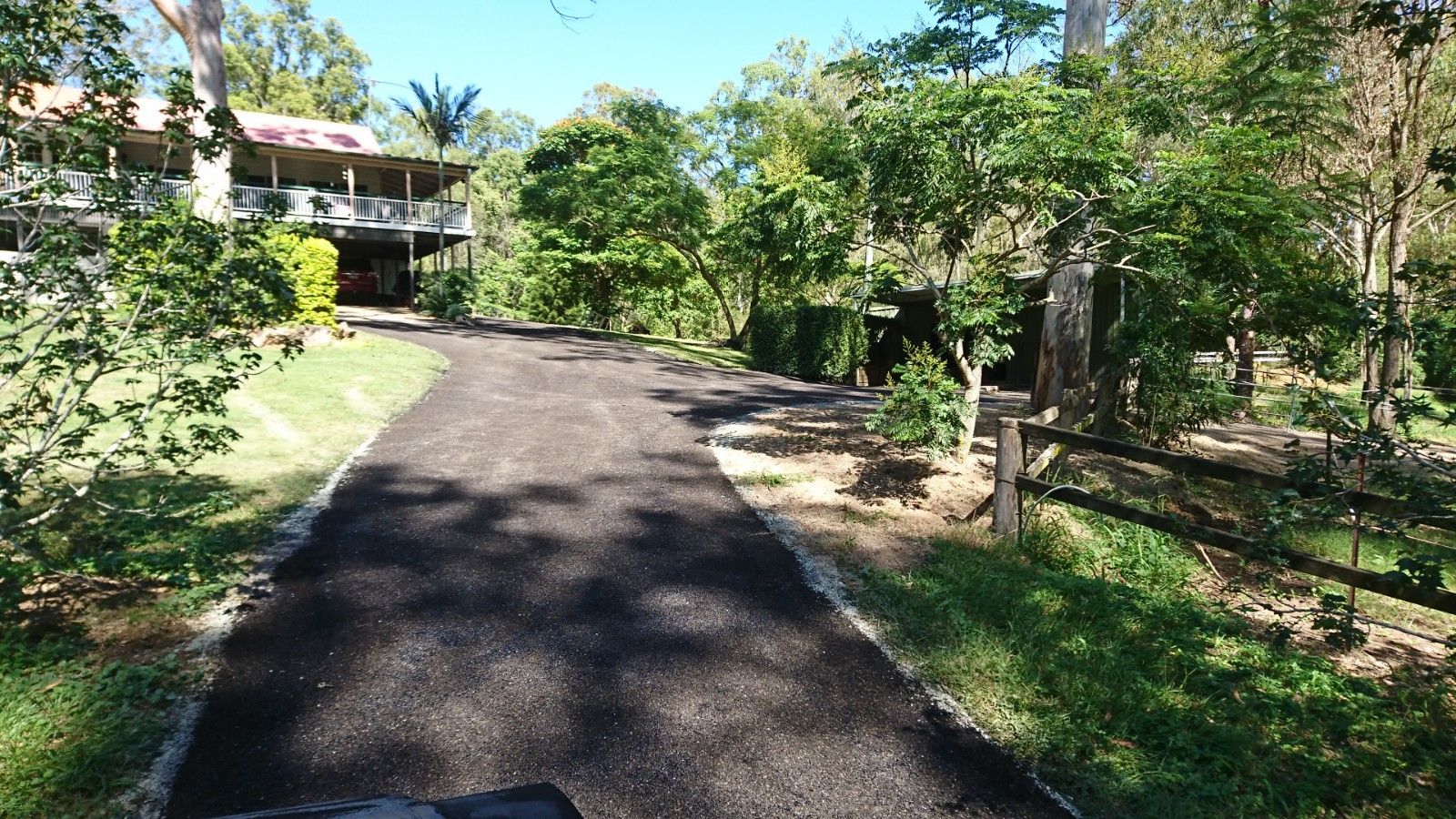 A driveway leading to a house surrounded by trees and grass.