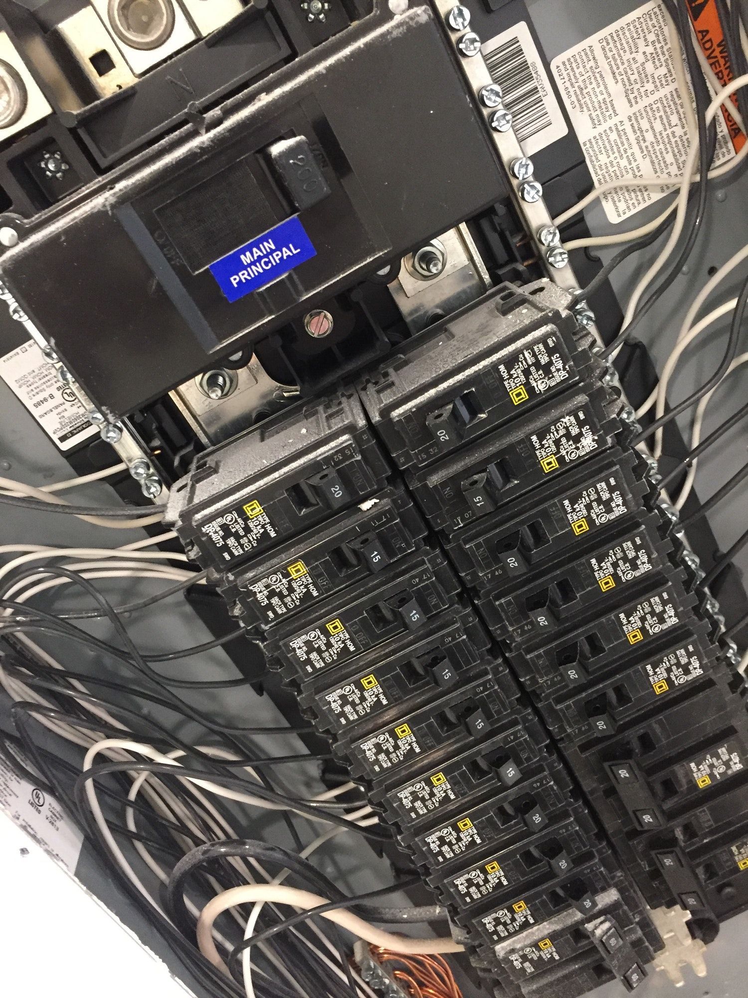 Electrical panel with rows of circuit breakers and wiring.