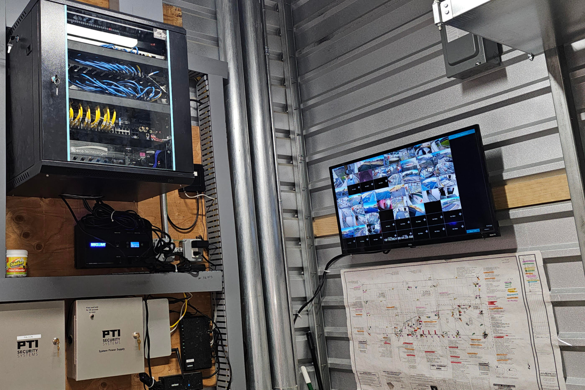 A room with a computer and a television on the wall.
