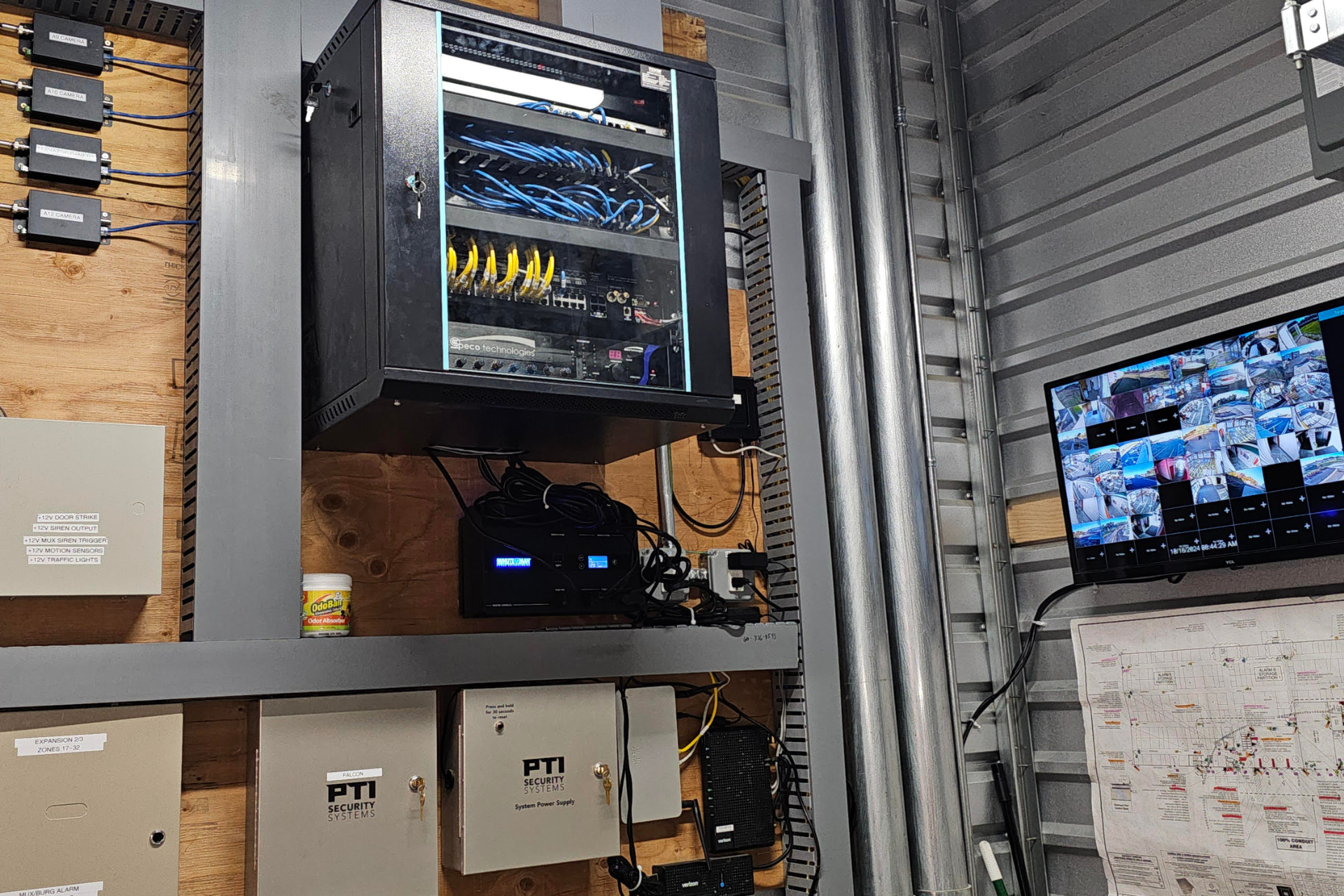 A room with a lot of electrical equipment and a tv on the wall.