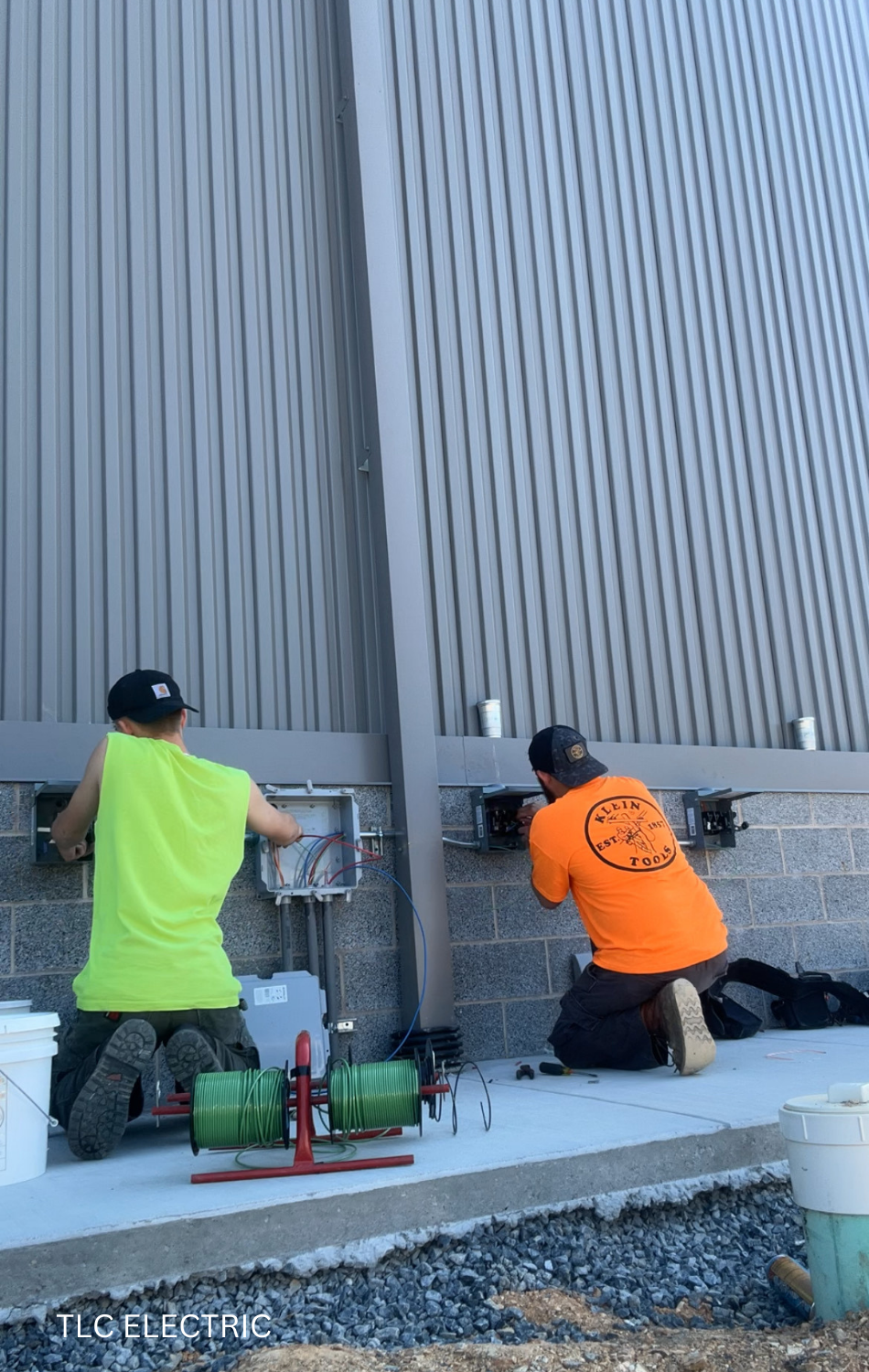 Two men are working on a fence in front of a building.