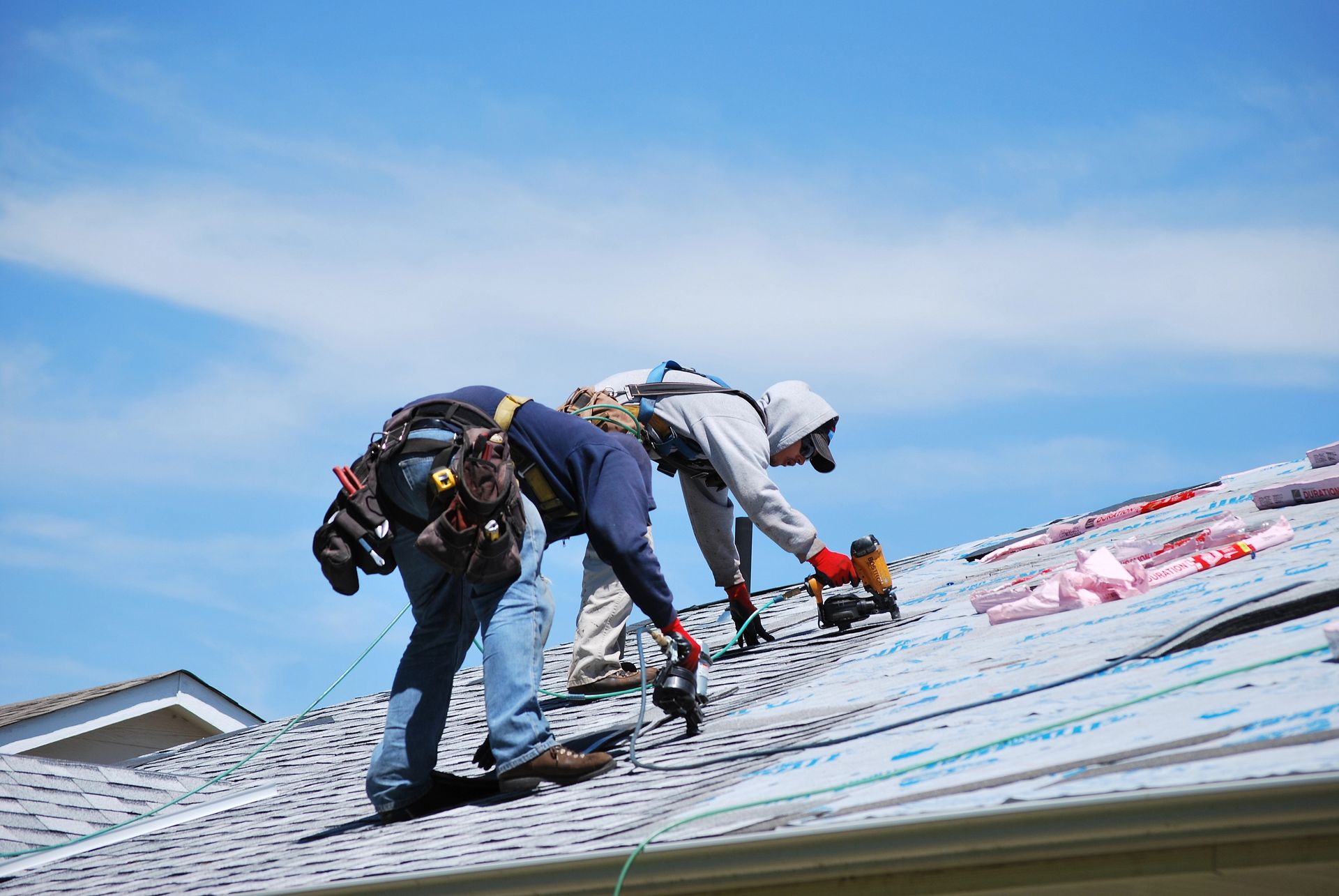 Two men are working on the roof of a house.