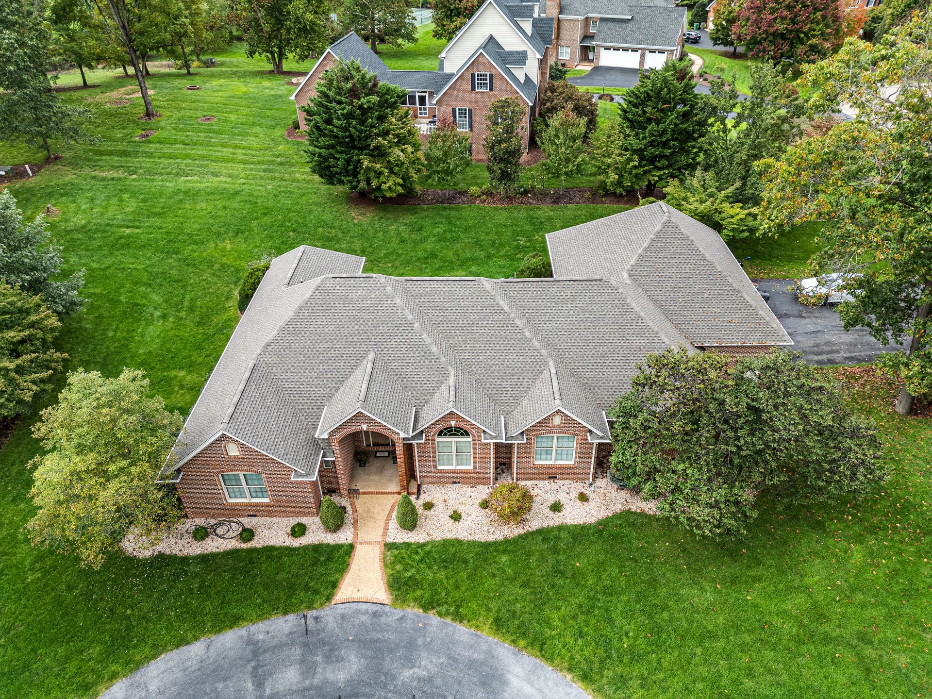 An aerial view of a large brick house surrounded by trees and grass.