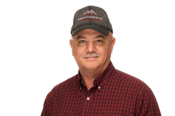 A man wearing a hat and a red shirt is standing in front of a white background.