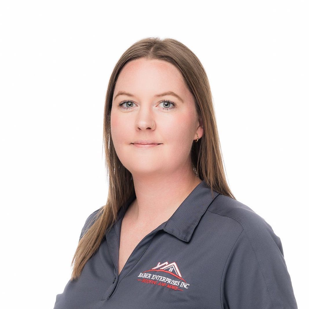 A woman is wearing a gray shirt with a mountain embroidered on it.