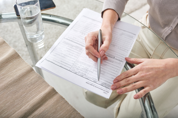 A person is writing on a piece of paper with a pen.