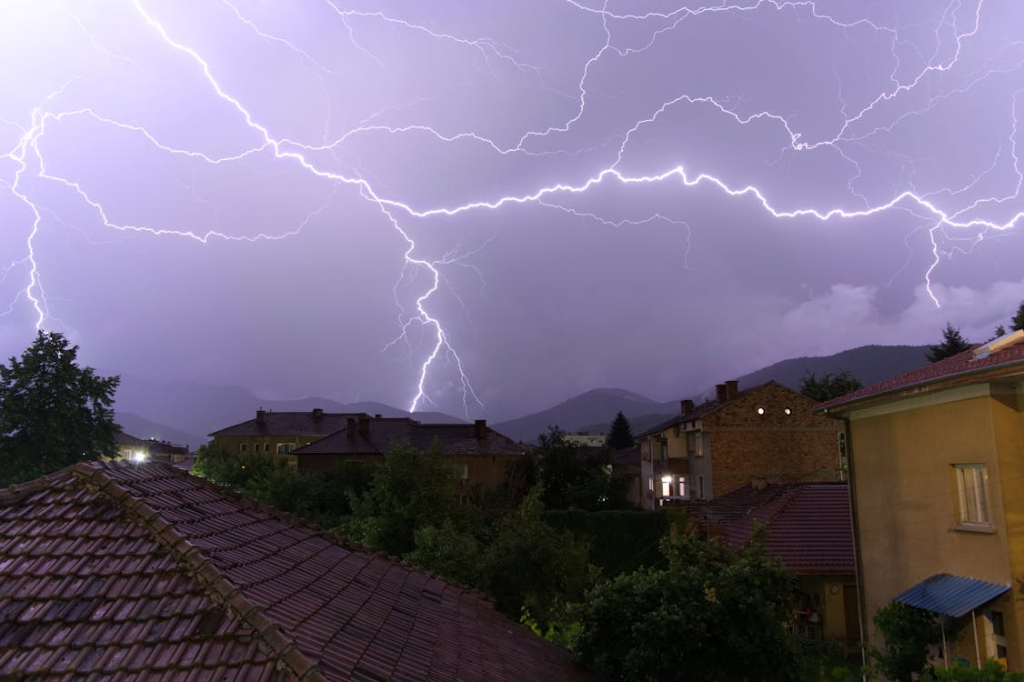 There is a lot of lightning in the sky over a house.