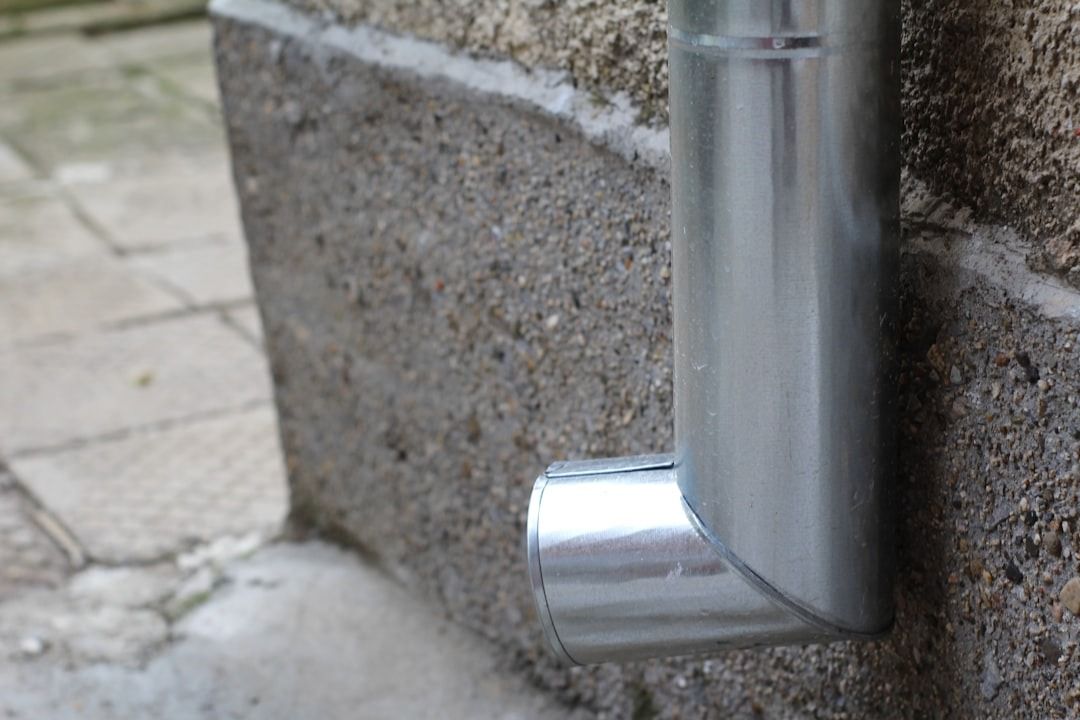 A close up of a metal pipe on the side of a building.