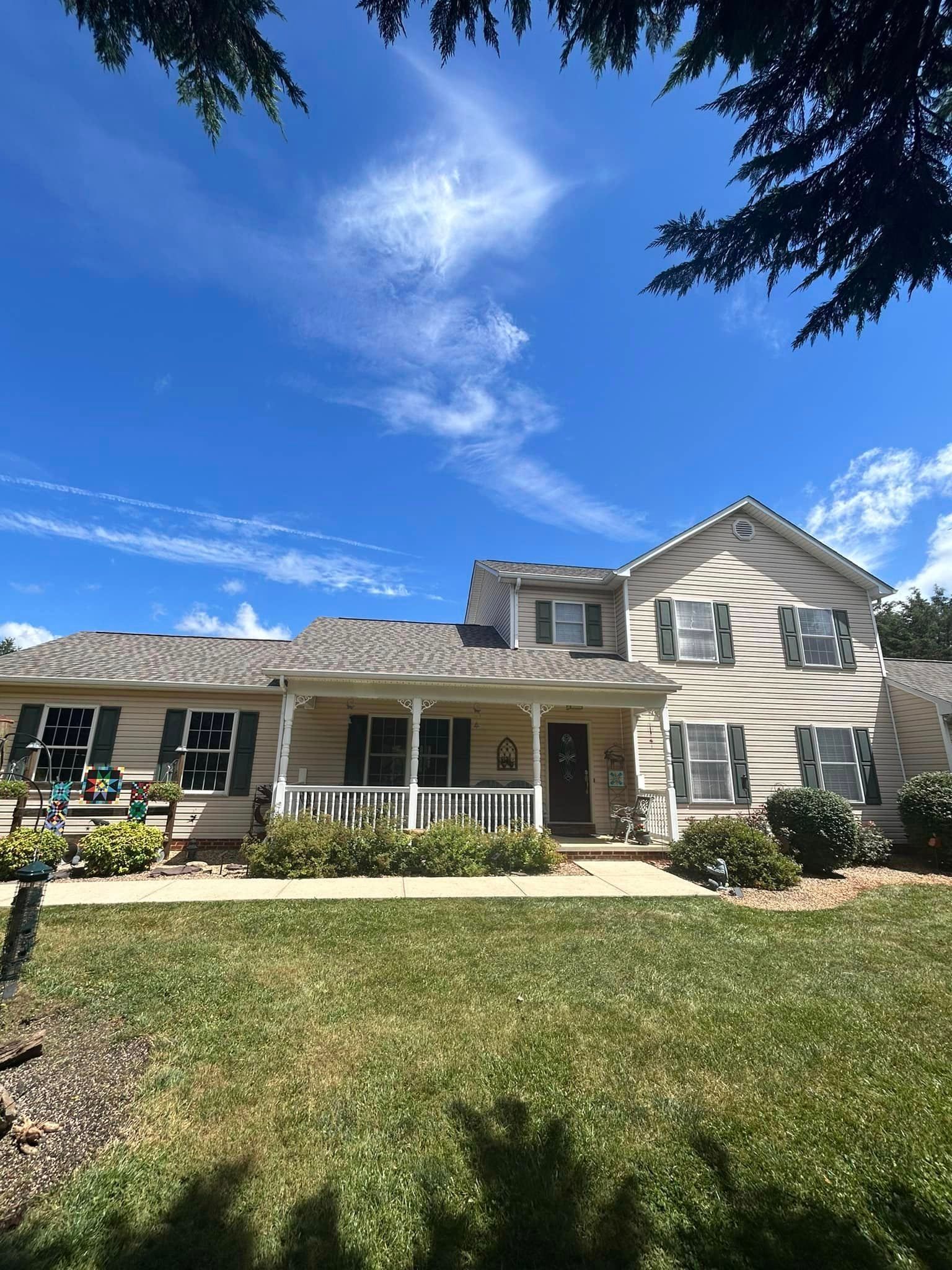 A large house with a porch and a blue sky in the background