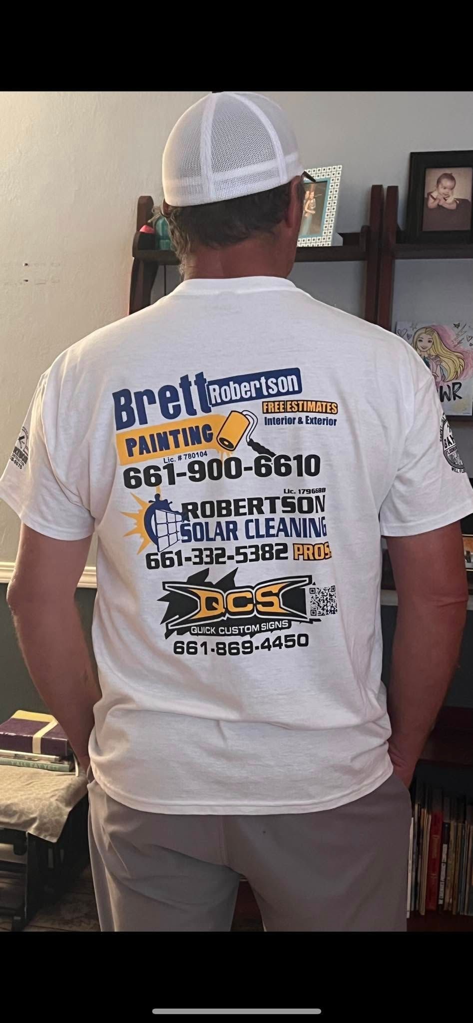 A man wearing a white t-shirt and a white hat is standing in a living room.