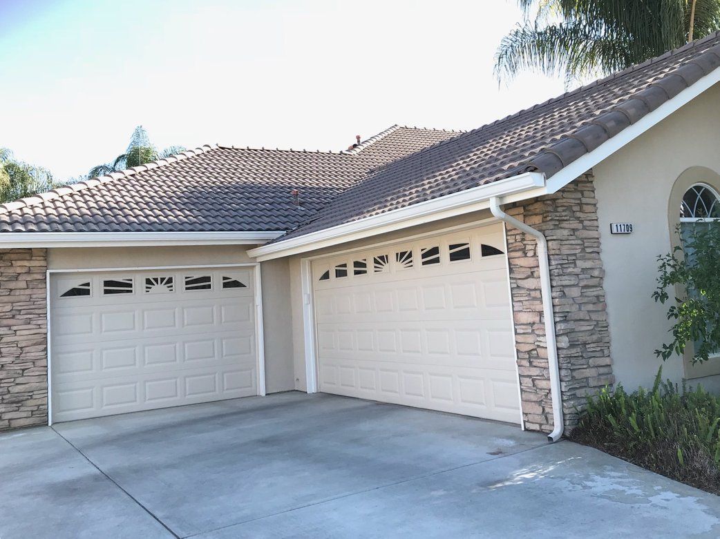 A house with two garage doors and a driveway in front of it.