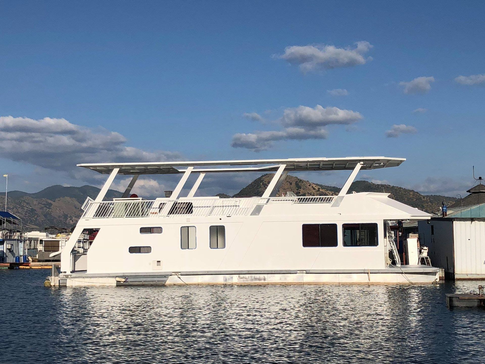 A large white houseboat is docked in the water.
