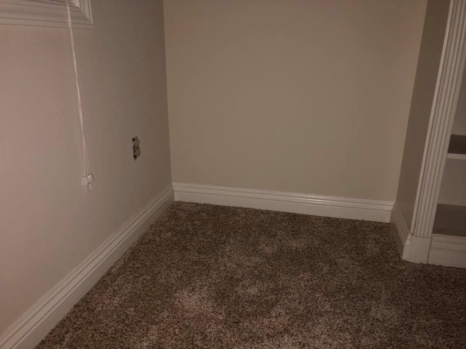 An empty room with a carpeted floor and white trim.