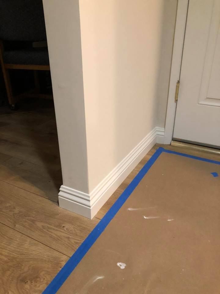 A corner of a room with a door and a piece of paper on the floor.