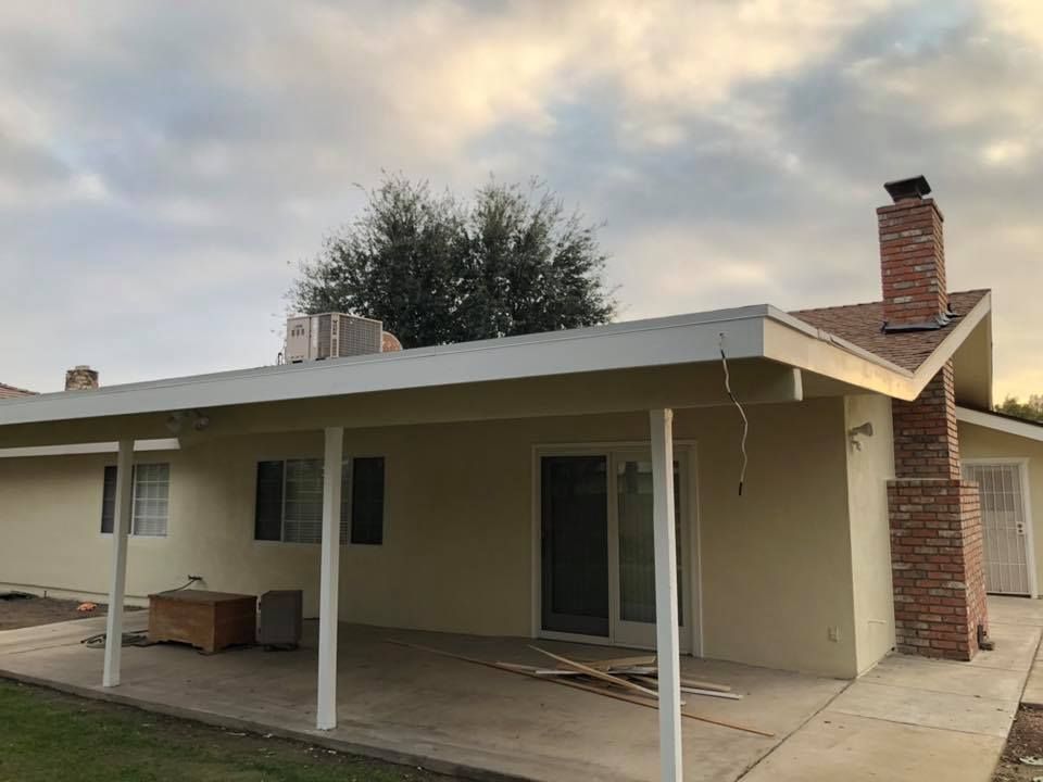 The back of a house with a covered patio and a chimney.