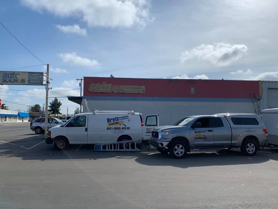 Two trucks are parked in front of a building in a parking lot.