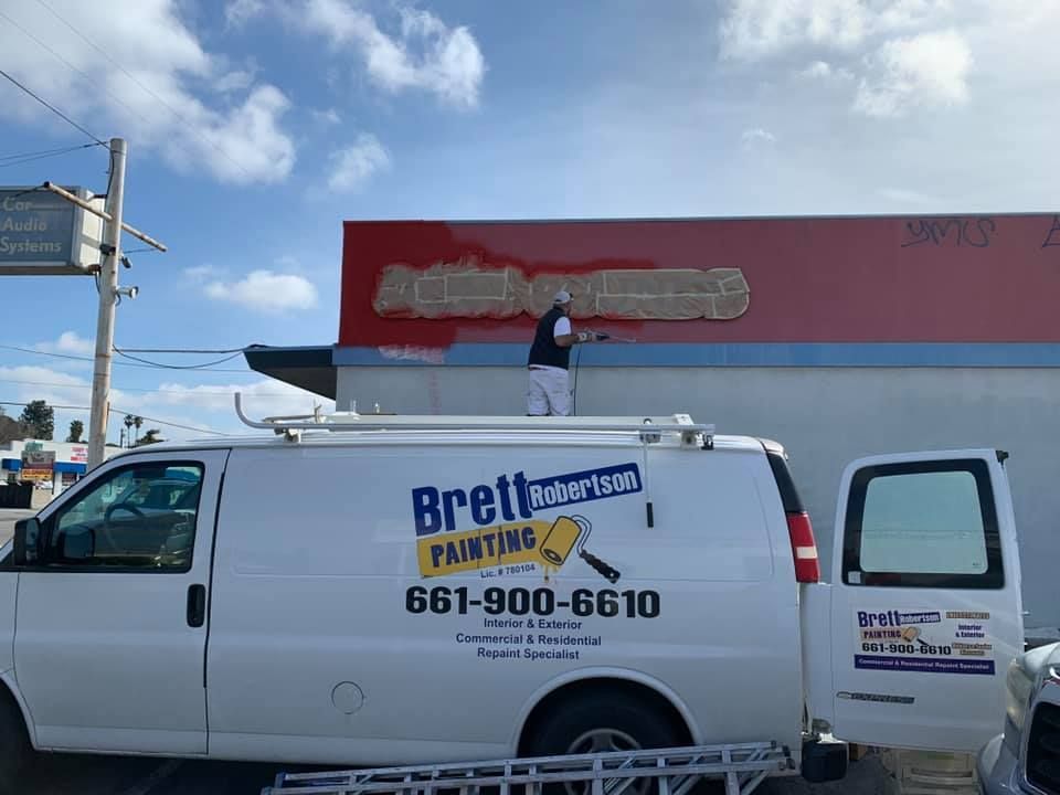 A brett painting van is parked in front of a building.