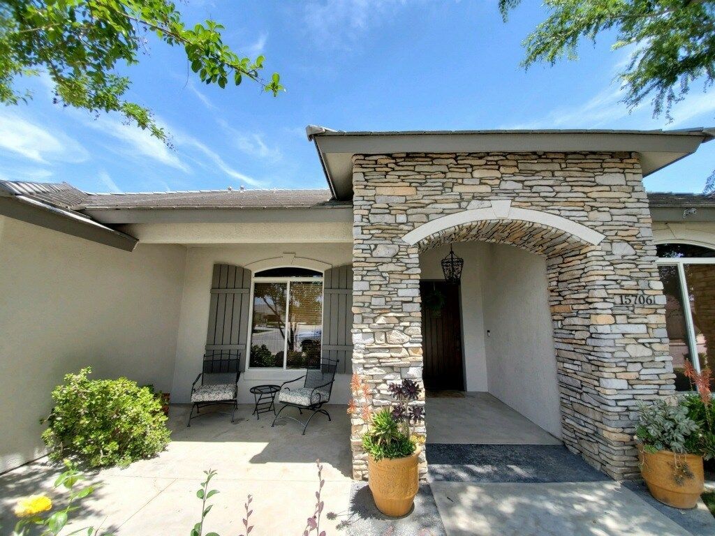 The front of a house with a stone wall and a patio