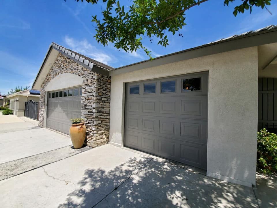 A house with two garage doors and a stone wall