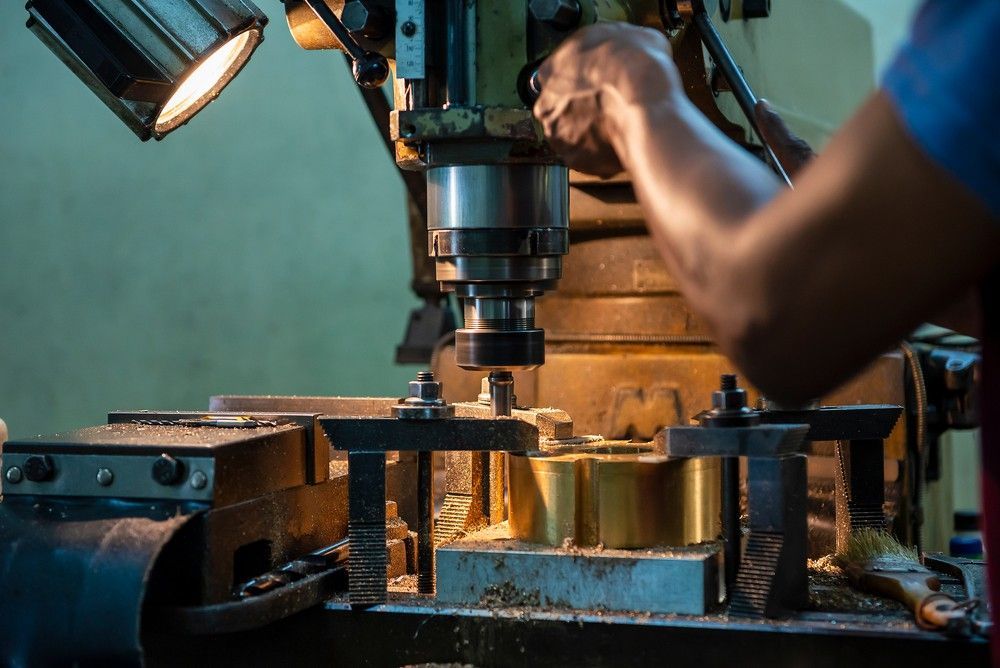 A Man is Working on a Machine in a Factory — Drinnan's Diesel & Automotive Repairs In Gladstone Central, QLD