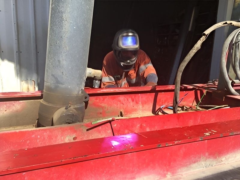 A Man Wearing a Welding Helmet is Working on a Red Object — Drinnan's Diesel & Automotive Repairs In Gladstone Central, QLD