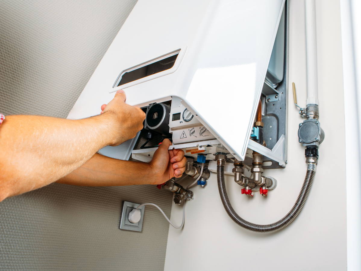 Person adjusting a white wall-mounted gas boiler, focusing on the internal components.