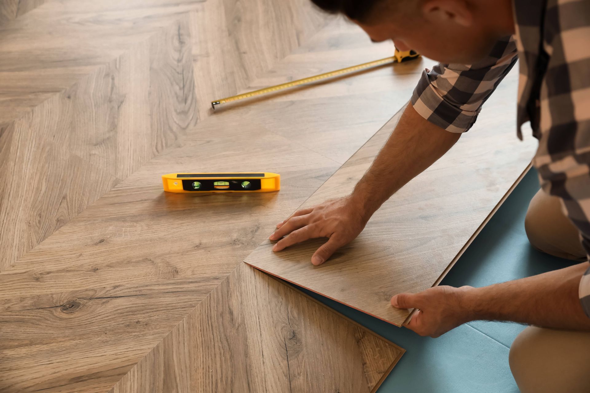 A man is installing a wooden floor in a room.