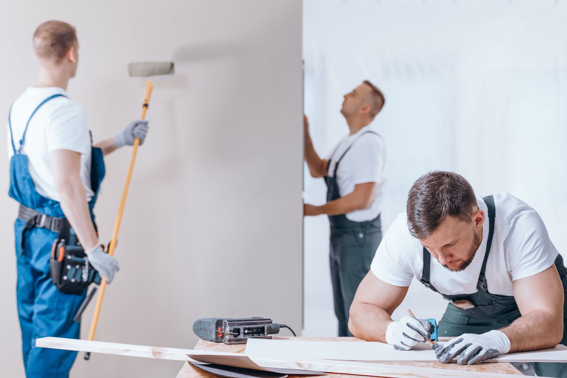 A group of men are painting a wall.