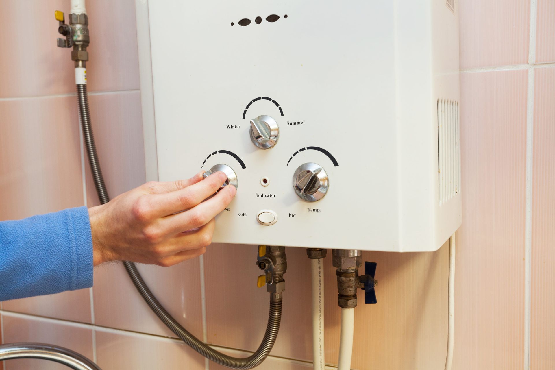 A person is adjusting a water heater in a bathroom.