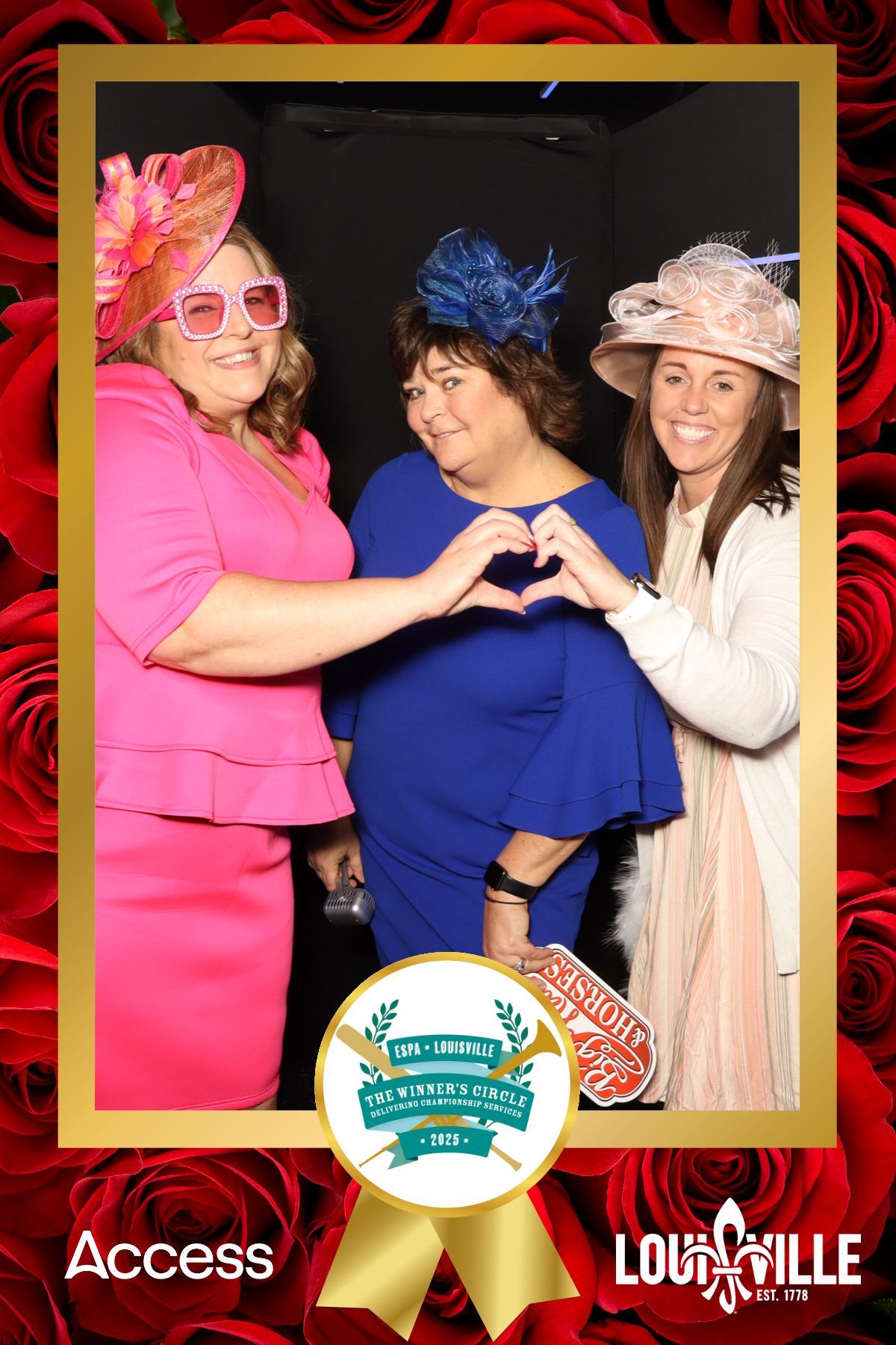 Three women are making a heart shape with their hands in a photo booth.