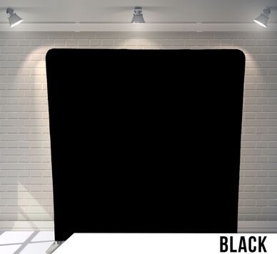A black backdrop is sitting in front of a white brick wall.