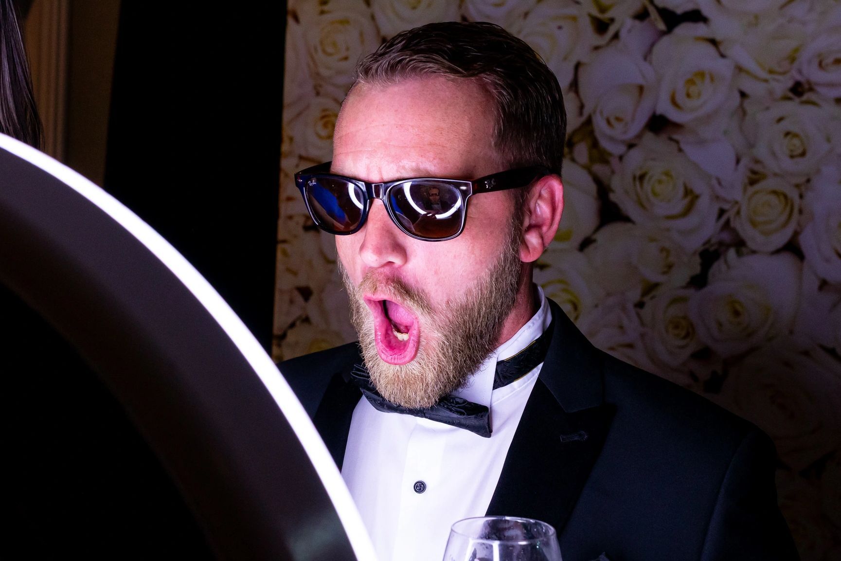 A man in a tuxedo and sunglasses is taking a picture of himself.