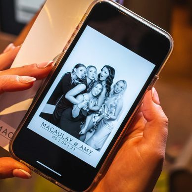 A person is holding a cell phone with a picture of macaulay and amy on it