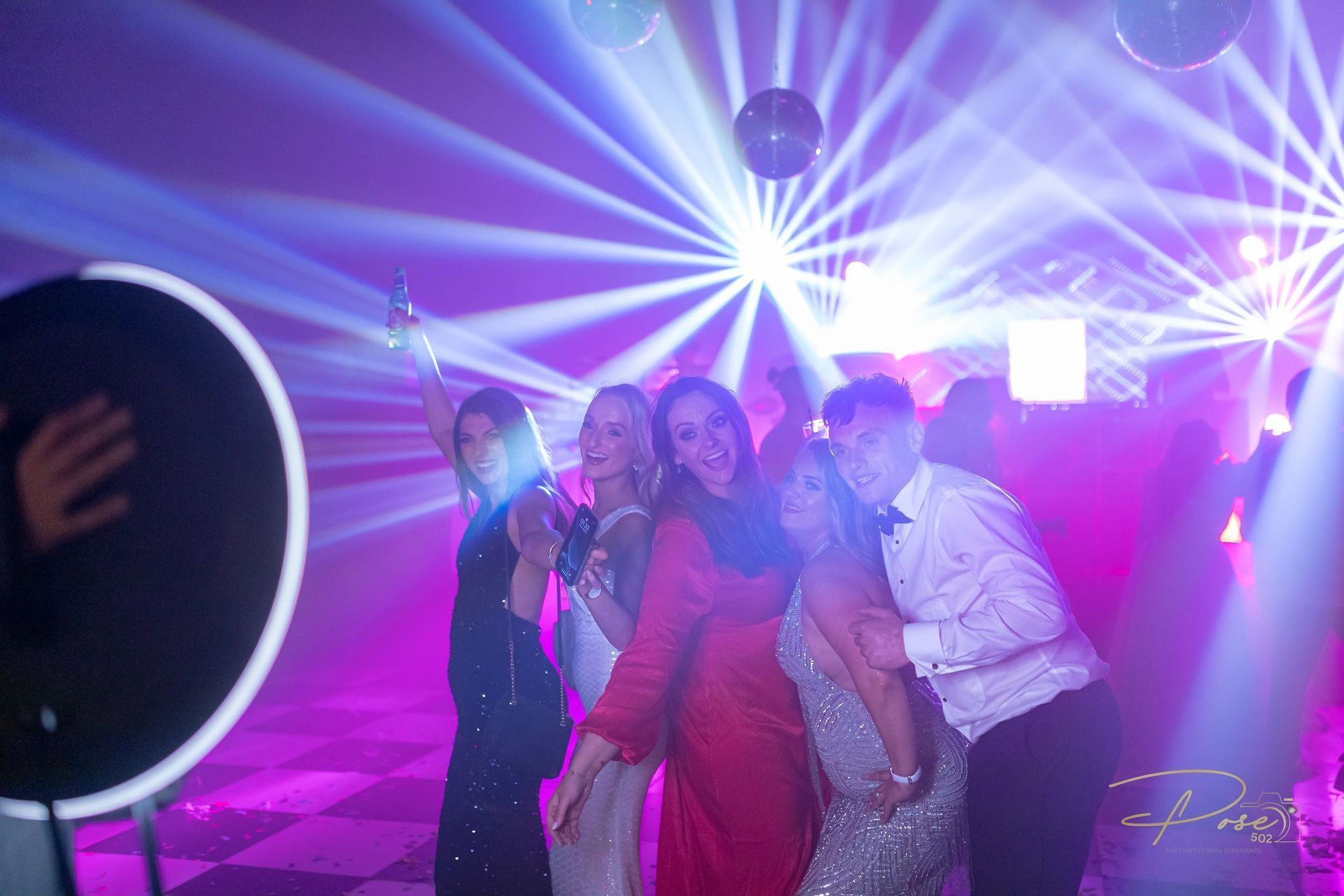A group of people are posing for a picture in front of a mirror at a party.