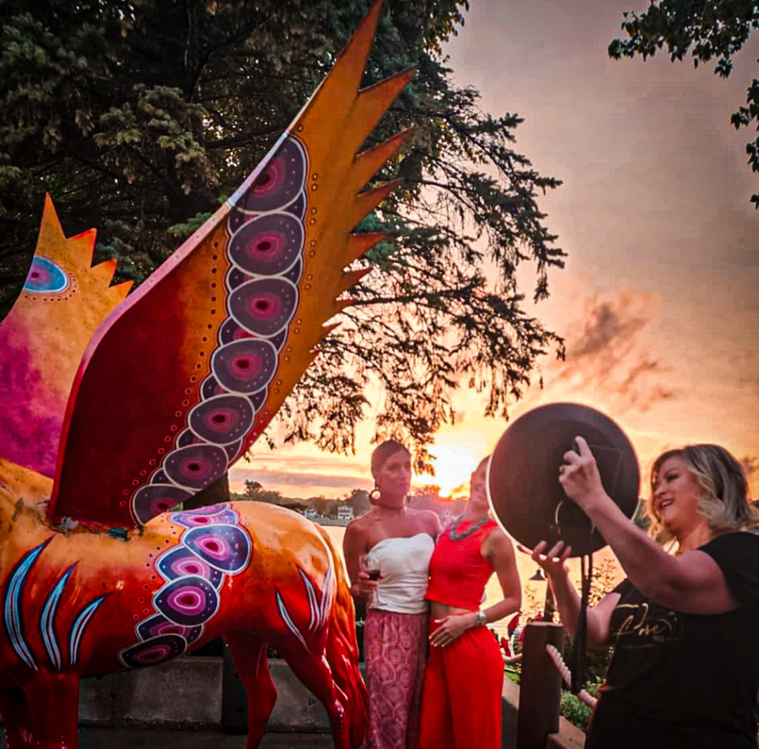 A group of women standing around a statue of a dragon