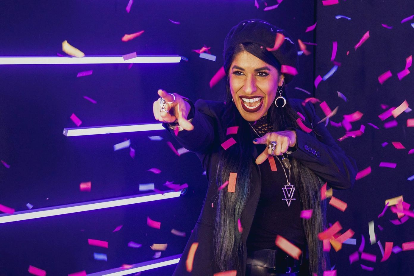 A woman is standing in front of a wall of confetti.