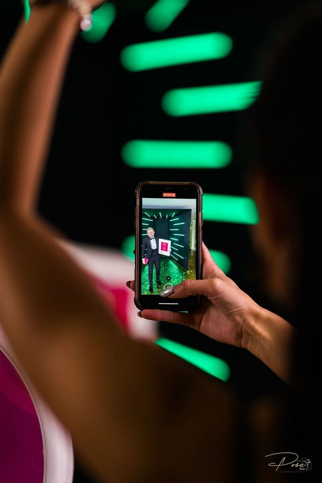 A woman is taking a picture of a man on her phone.