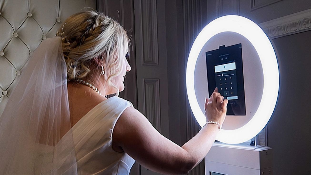 A bride is taking a picture of herself in a photo booth.