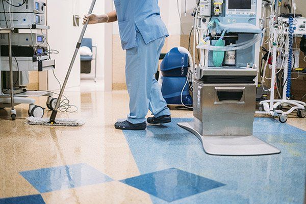 person wearing scrubs and mopping floor of medical clinic