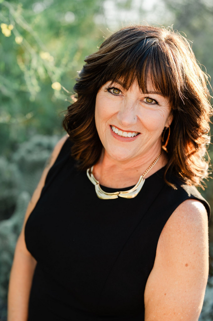 Portrait of a smiling woman in a black top outdoors with blurred greenery background
