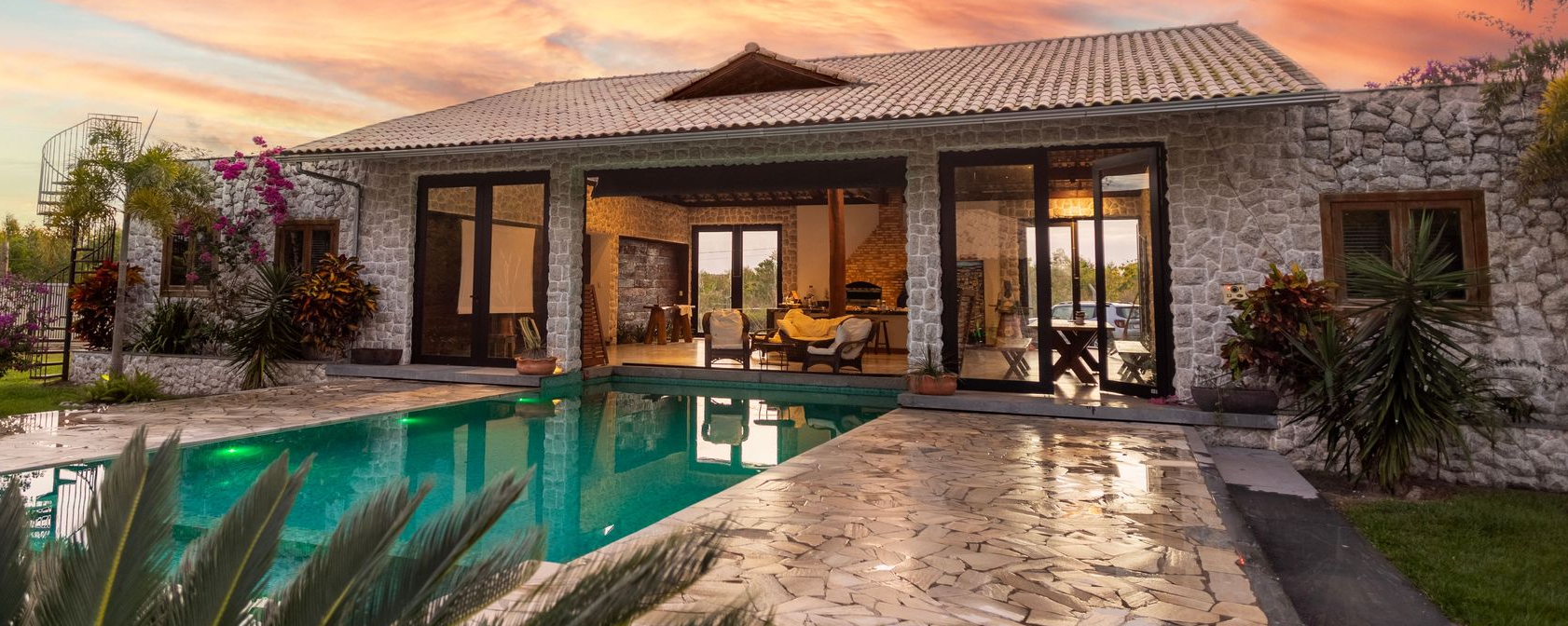 Single-story stucco house with desert landscaping and a warm sunset sky