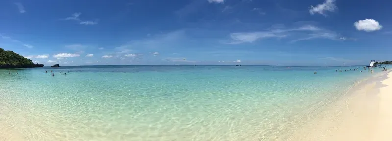 A panoramic view of a beach with people swimming in the ocean.