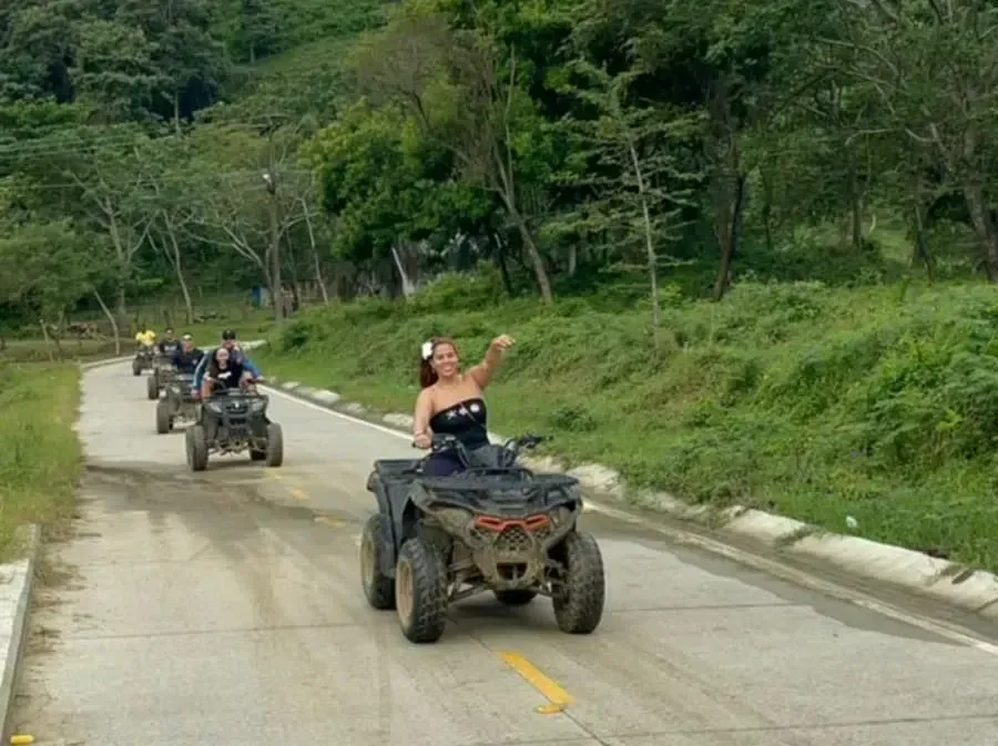 A group of people are riding atvs down a dirt road.