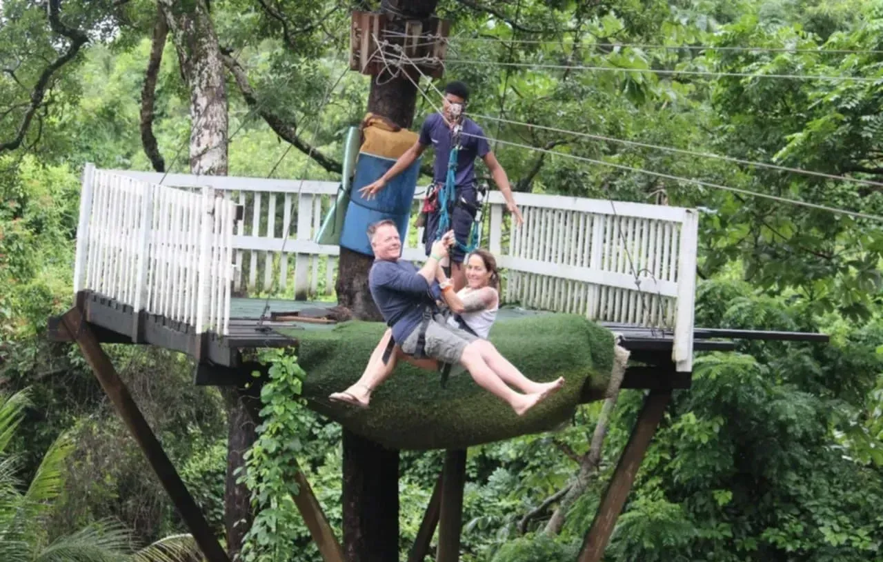 A man is carrying a woman on a zip line.