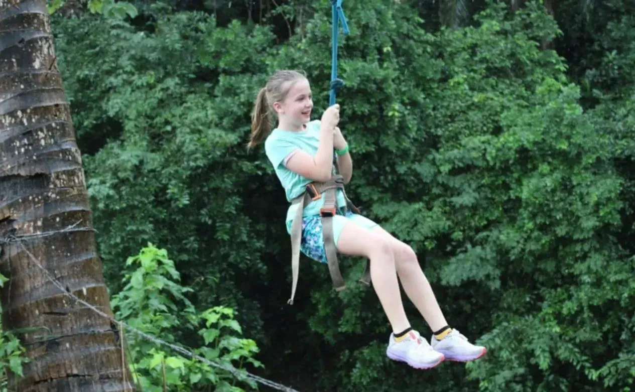 A young girl is flying through the air on a rope swing.