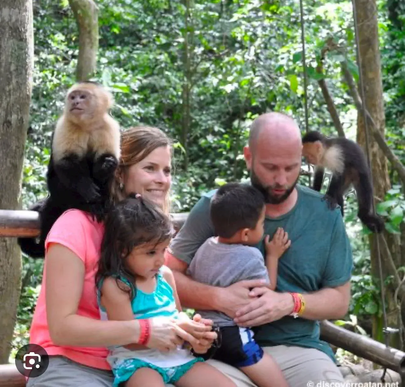 A man and woman holding a child with a monkey on their back